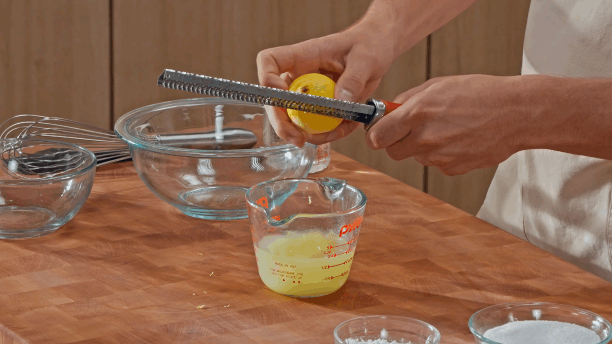 Nick DiGiovanni zesting a lemon into a liquid measuring cup of lemon juice.