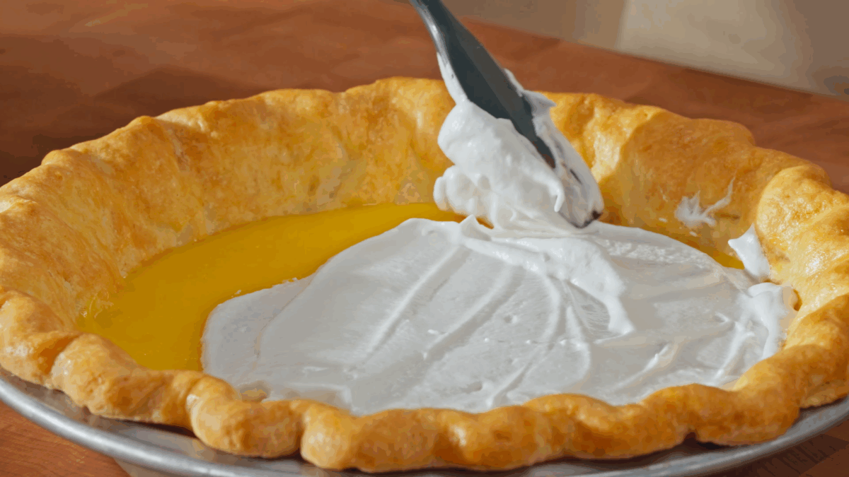 Nick DiGiovanni spreading Italian meringue over a lemon meringue pie.