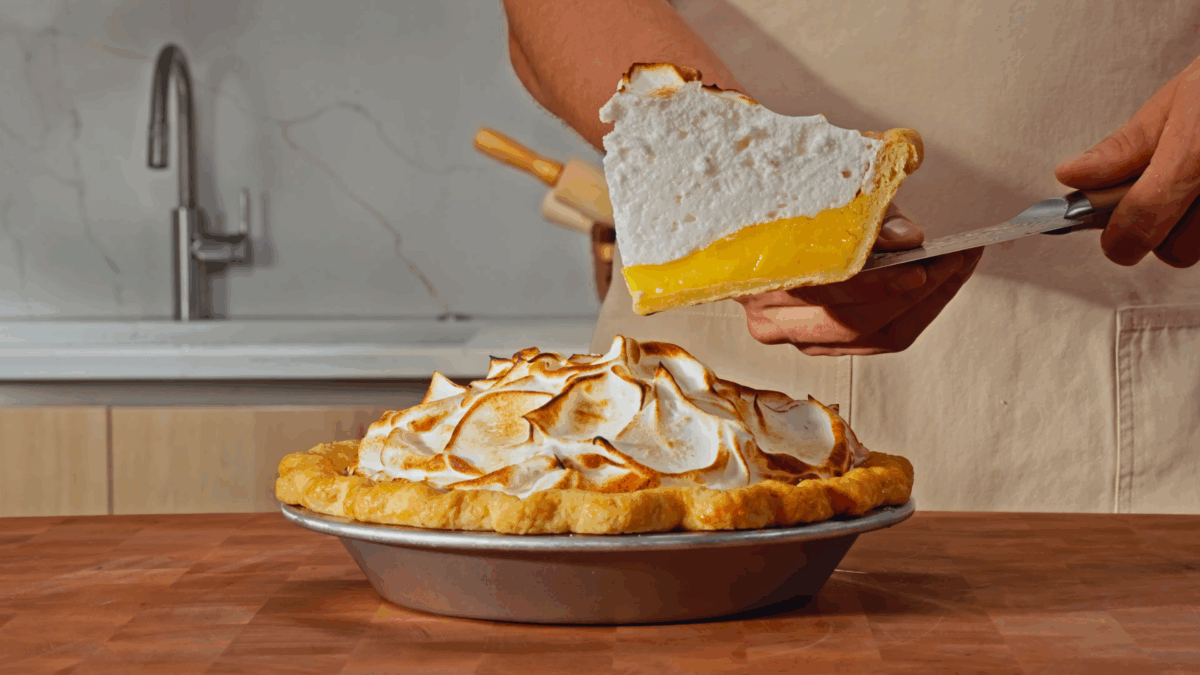 Nick DiGiovanni slicing a piece of lemon meringue pie from a whole pie.