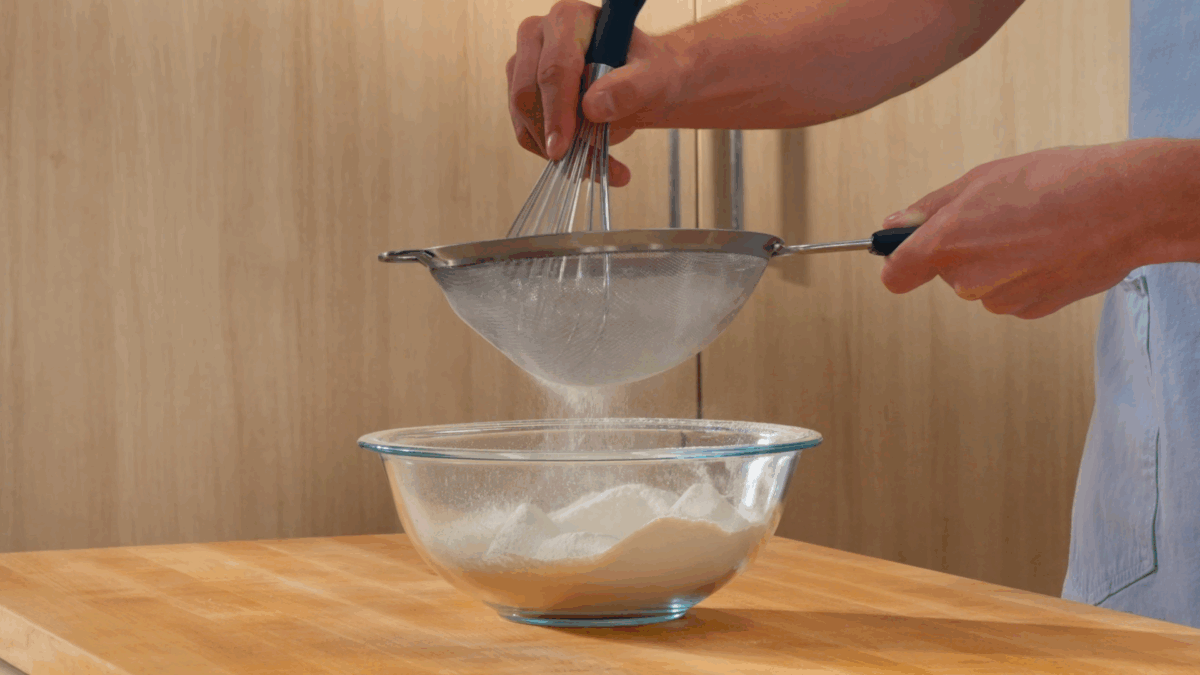 Nick DiGiovanni sifting dry vanilla birthday cake ingredients into a bowl. 
