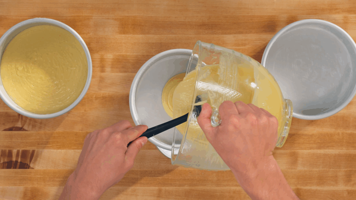 Nick DiGiovanni pouring cake batter into three greased cake pans. 