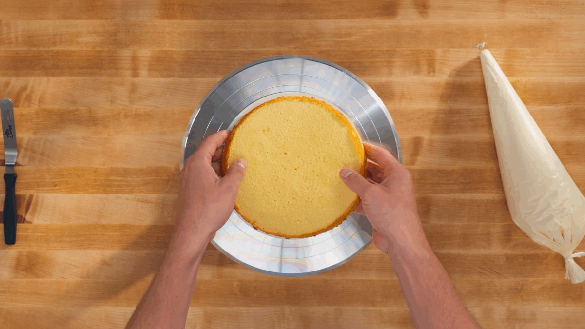 Nick DiGiovanni placing a vanilla cake layer on a cake stand. 