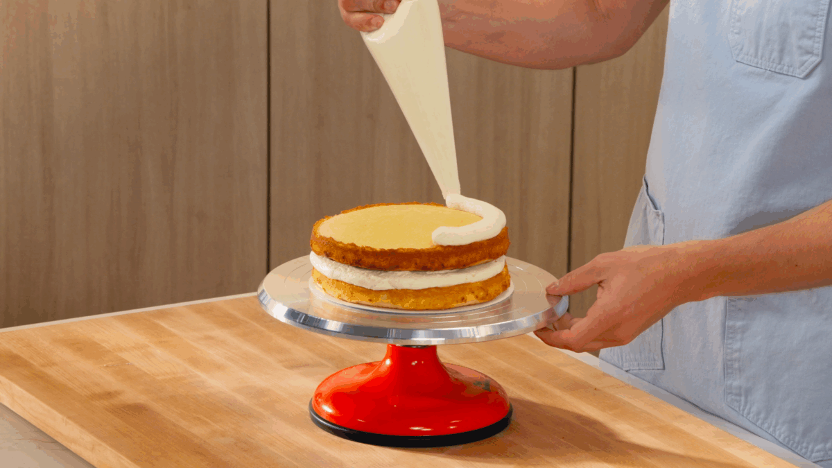 Nick DiGiovanni piping buttercream frosting on a vanilla birthday cake. 