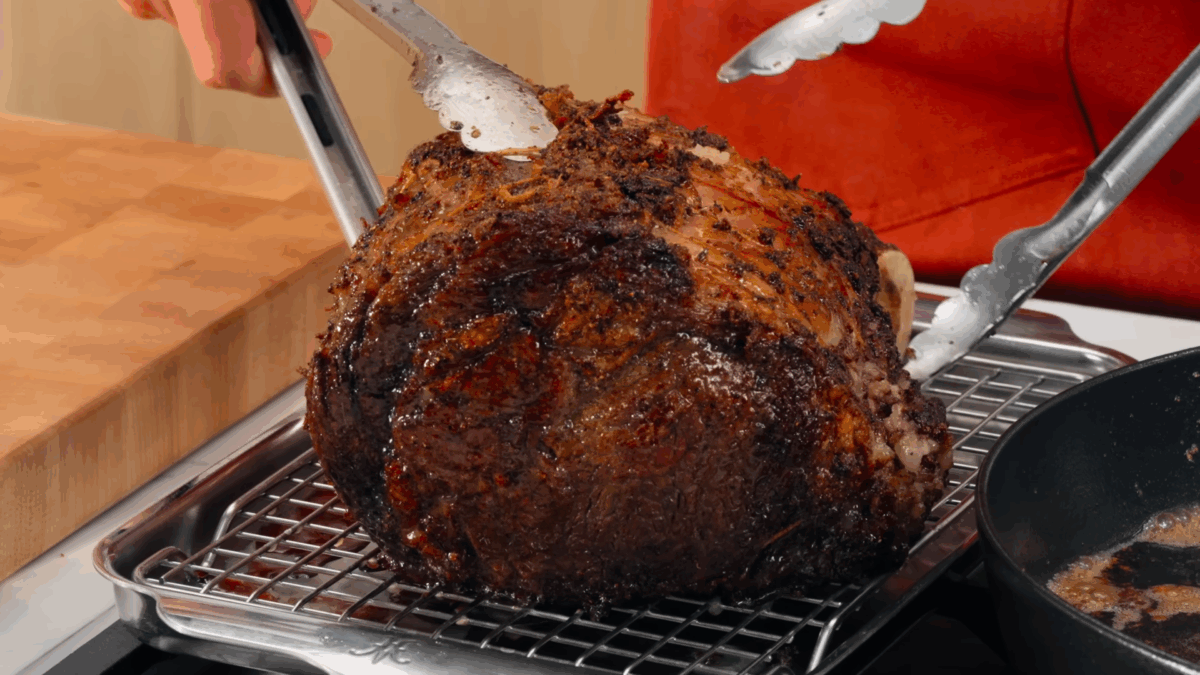 Nick DiGiovanni transferring a cooked prime rib roast to a wire rack over a baking sheet.