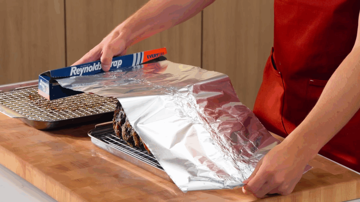 Nick DiGiovanni covering a roasted prime rib with aluminum foil.