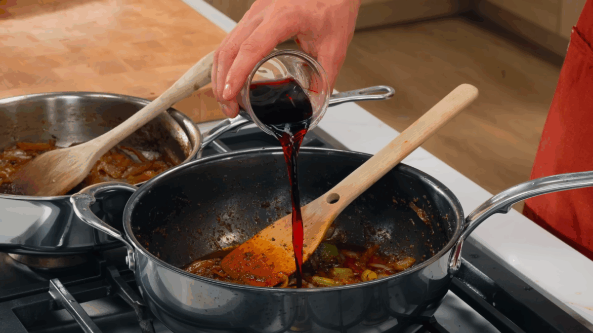 Nick DiGiovani pouring red wine into a pan to make au jus.