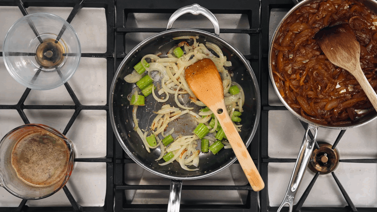 White onions and celery cooking in a sauté pan.