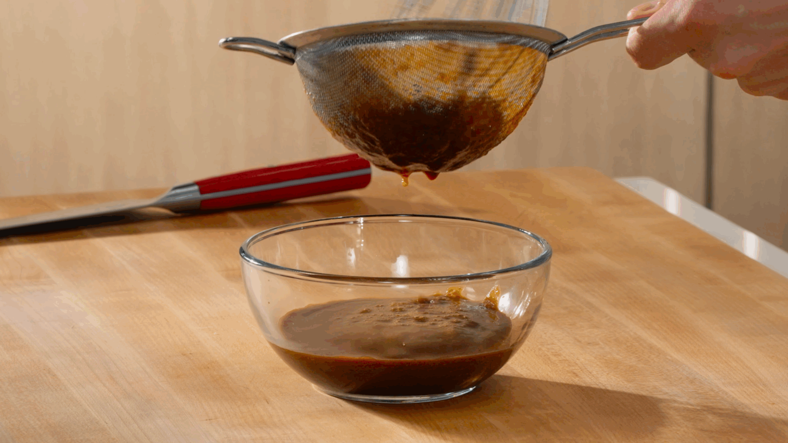 Nick DiGiovanning pouring blended tonkatsu sauce through a fine mesh sieve. 