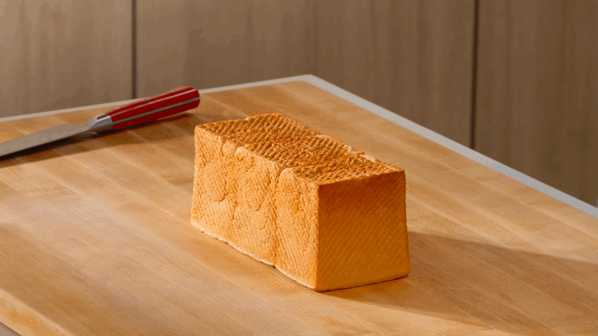 A shokupan loaf cooling on a wooden cutting board. 