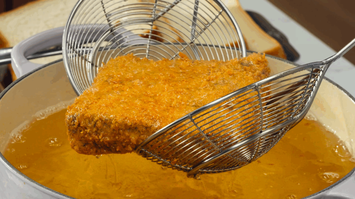 Nick DiGiovanni lifting a fried panko-crusted Wagyu piece from a pot of oil. 