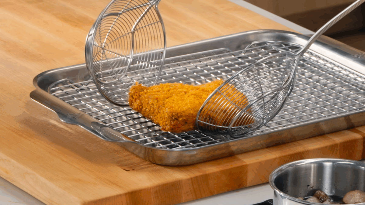 Nick DiGiovanni placing a fried panko-crusted Wagyu cutlet to a wire rack. 