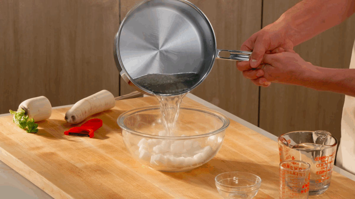 Nick DiGiovanni pouring pickling liquid over chopped daikon pieces in a bowl.