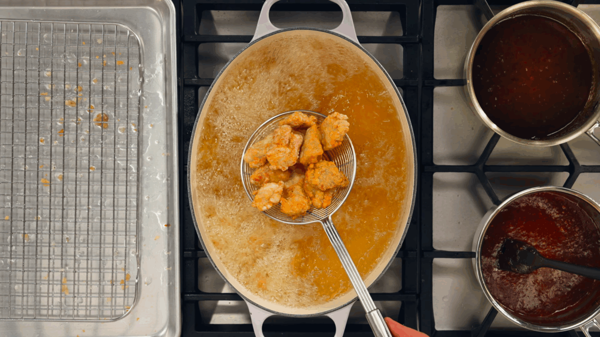 Nick DiGiovanni lifting Korean fried chicken pieces from a pot of oil.