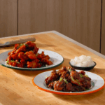 Two plates of Korean fried chicken next to a bowl of pickled daikon.
