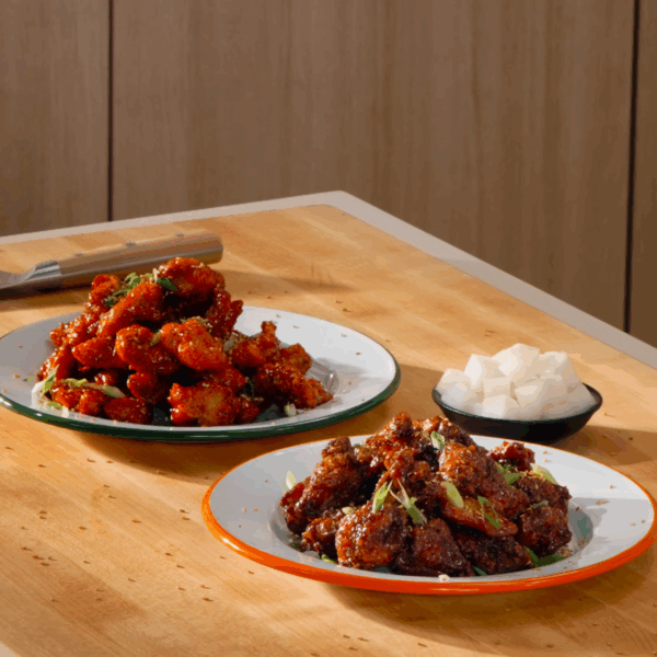 Two plates of Korean fried chicken next to a bowl of pickled daikon.