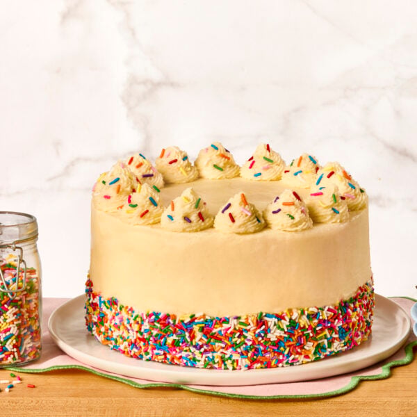 A three-layer vanilla birthday cake decorated with sprinkles.