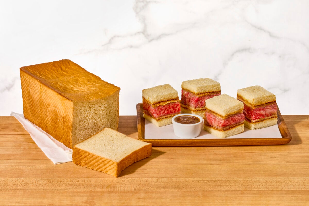 Wagyu katsu sando pieces on a platter next to a loaf of Japanese milk bread.