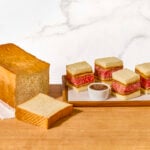 Wagyu katsu sando pieces on a platter next to a loaf of Japanese milk bread.