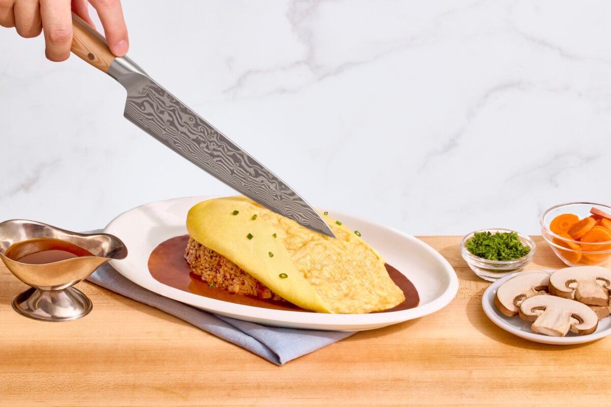 Nick DiGiovanni slicing into the omelet of plated omurice.