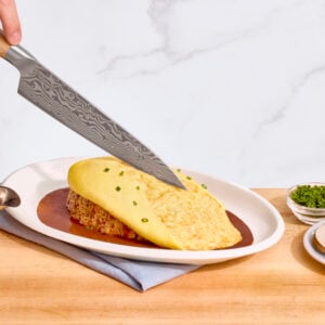 Nick DiGiovanni slicing into the omelet of plated omurice.