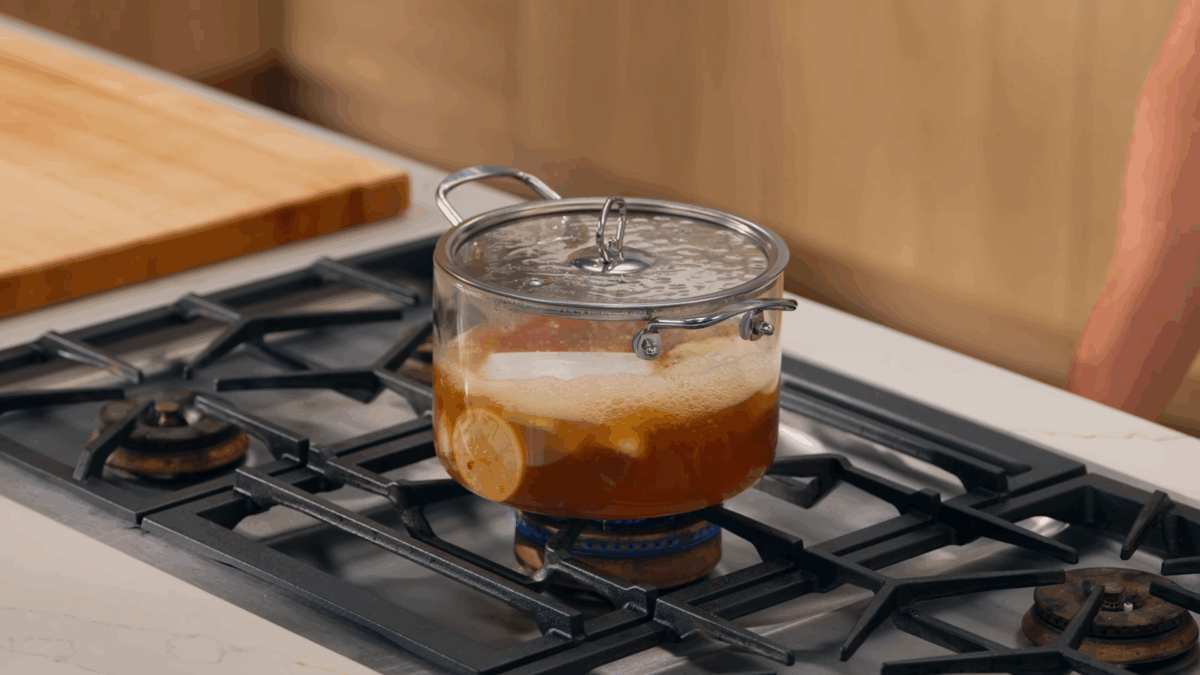 Chicken poaching in a pot on a stovetop.