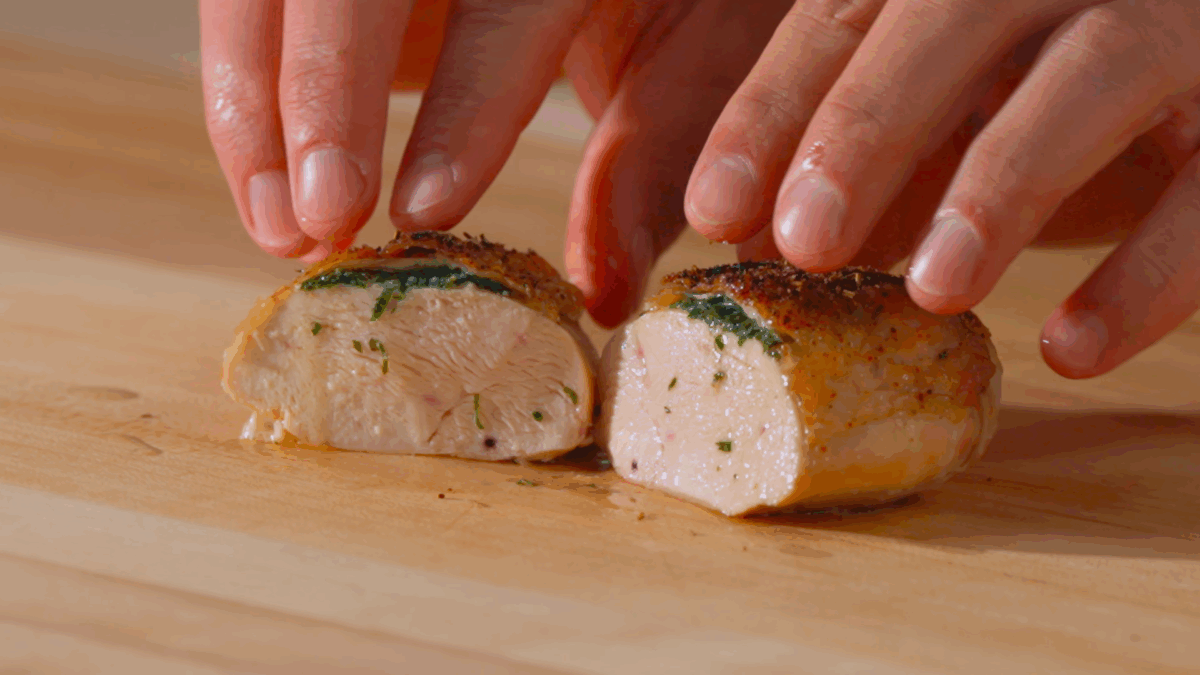 Nick DiGiovanni pulling two halves of a sliced, baked chicken breast apart.