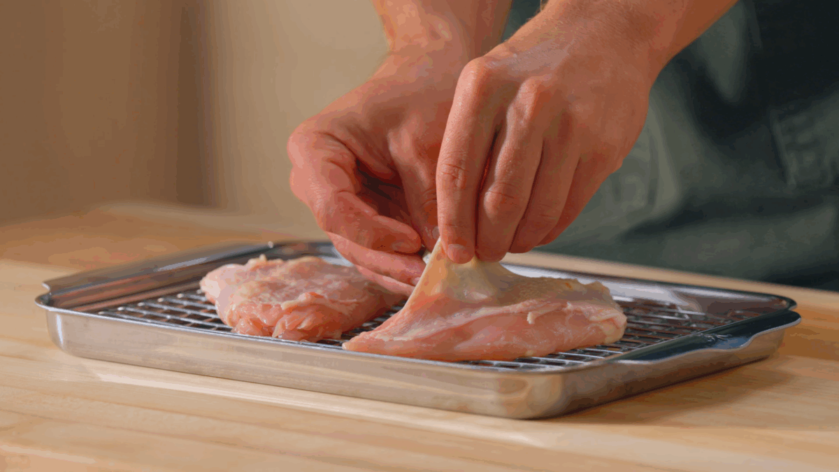 Nick DiGiovanni tucking compound butter under chicken skin.