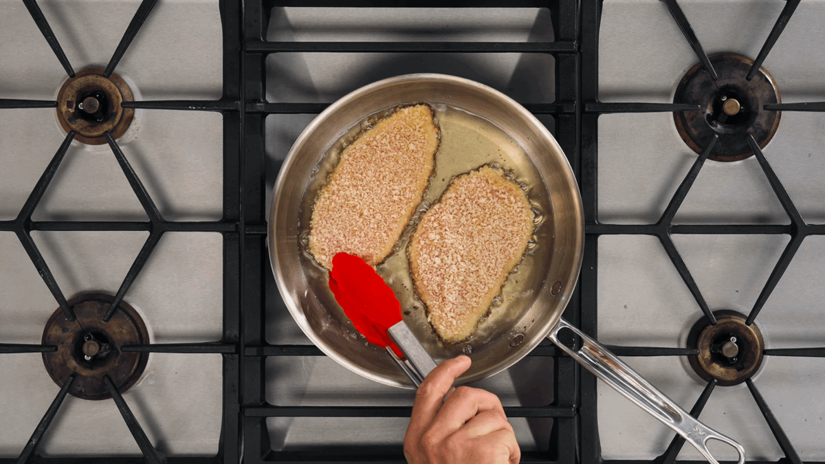 Nick DiGiovanni frying two breaded chicken cutlets in oil.