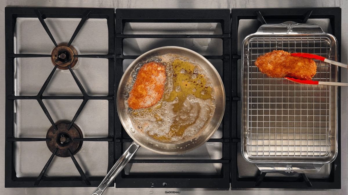 Nick DiGiovanni transferring breaded chicken cutlets from a pan to a wire rack.