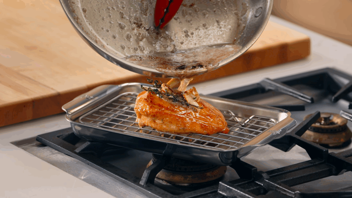 Nick DiGiovanni pouring butter over pan-fried chicken on a wire rack.