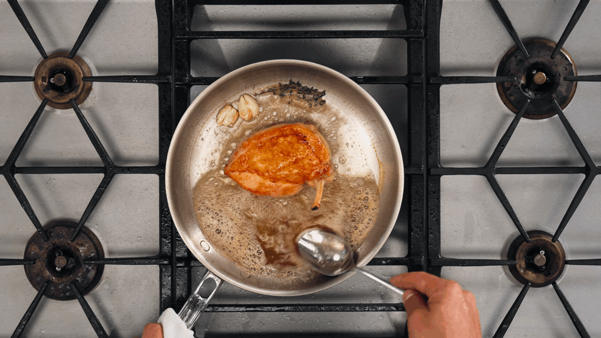Nick DiGiovanni basting chicken with butter in a pan.