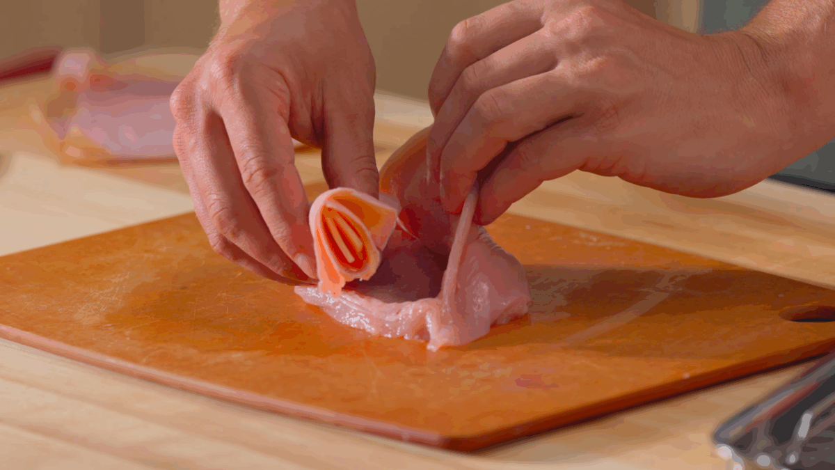 Nick DiGiovanni stuffing a raw chicken breast with ham and cheese.