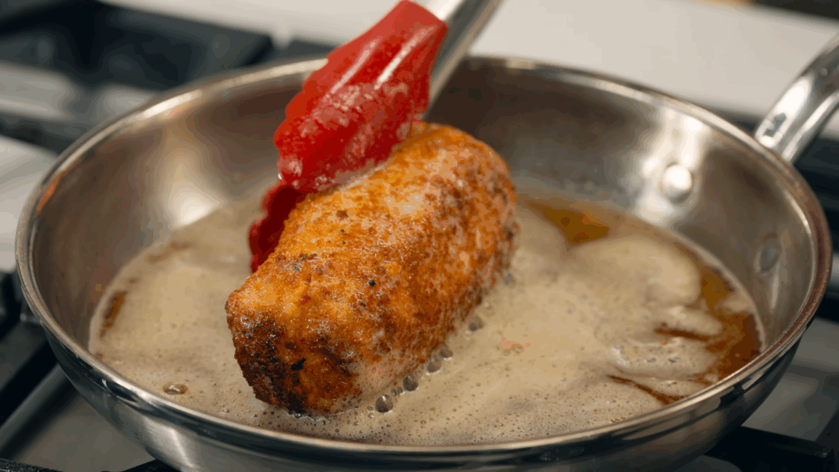 Nick DiGiovanni cooking a stuffed chicken breast in a pan on the stovetop.