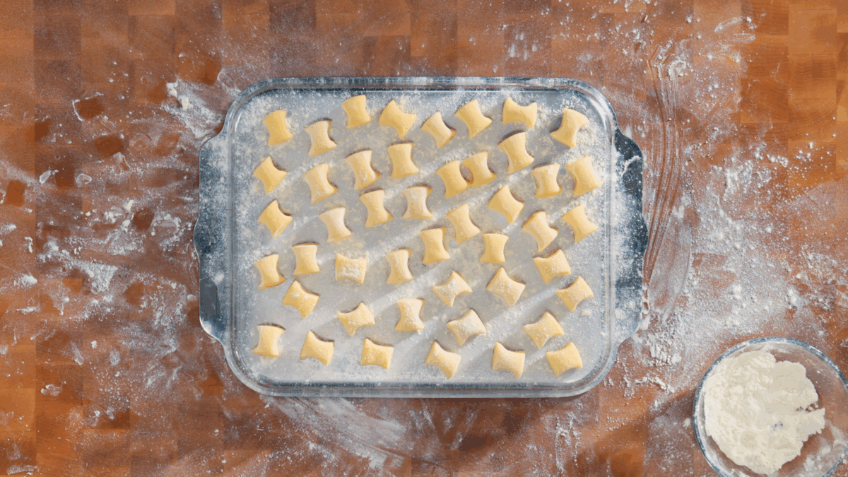 Uncooked gnocchi on an upside down floured sheet pan.