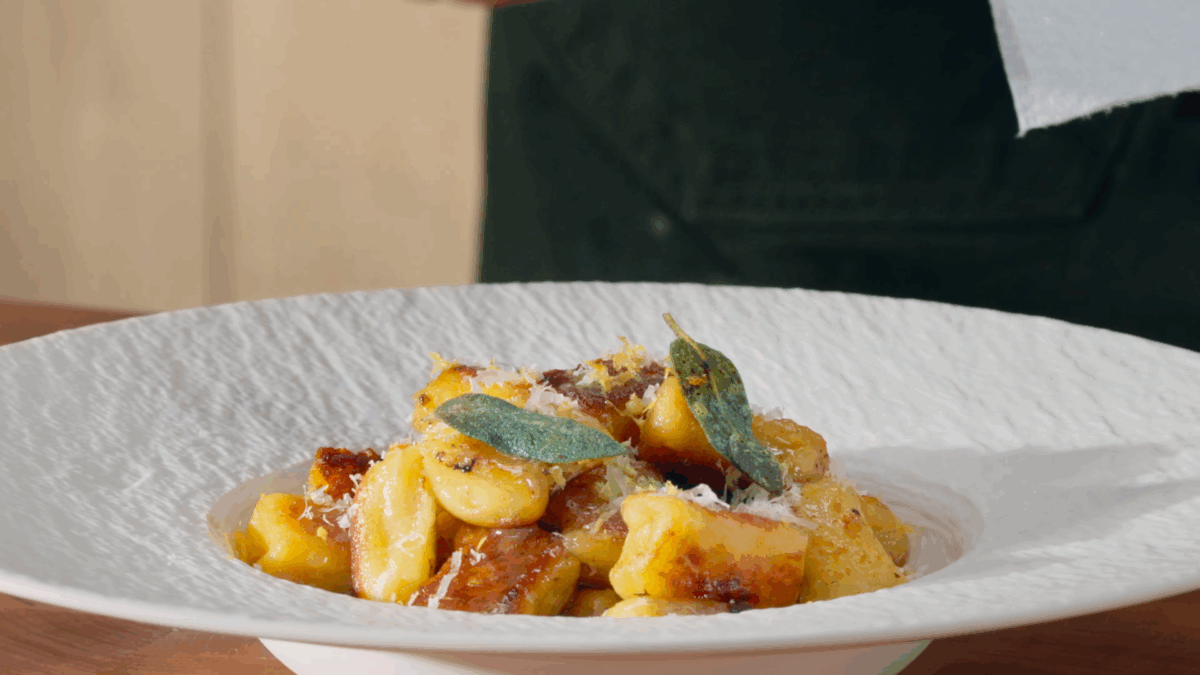 A bowl of homemade gnocchi topped with crispy sage leaves. 