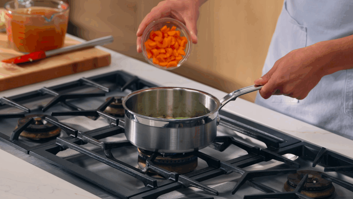 Nick DiGiovanni pouring carrots into a pot to make demi-glace. 