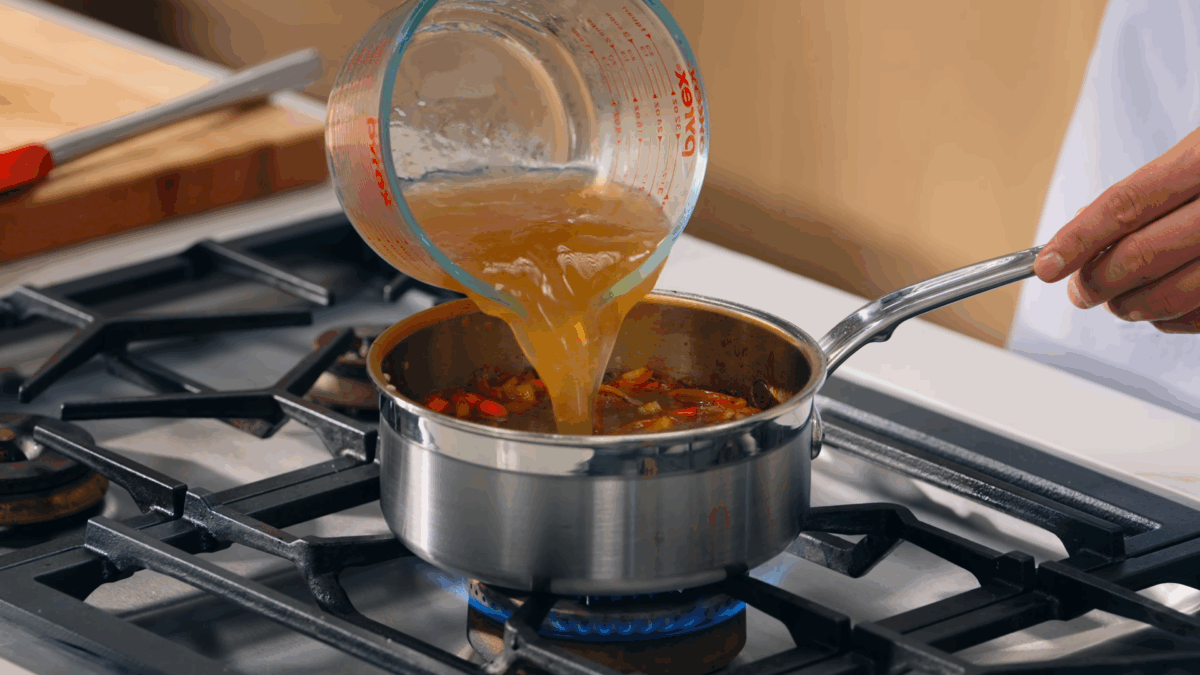 Nick DiGiovanni pouring beef broth into a pot. 