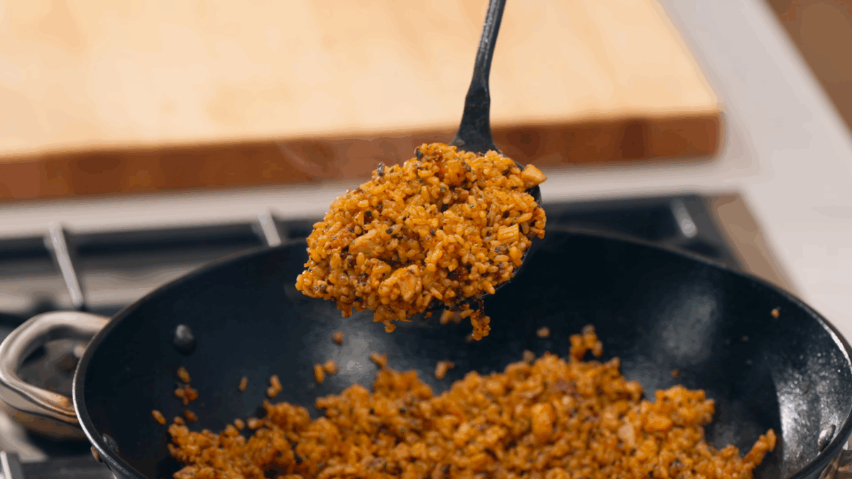 Nick DiGiovanni lifting a spoonful of chicken fried rice from a skillet. 