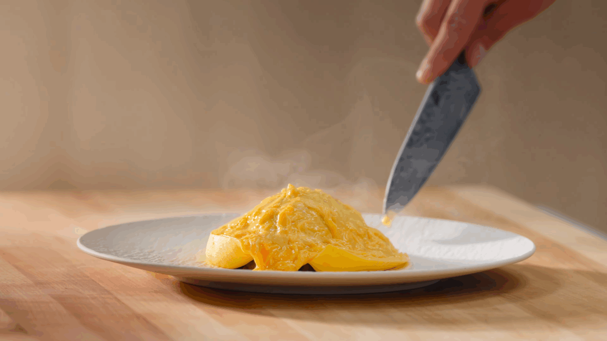 Nick DiGiovanni slicing into the omelet of omurice. 