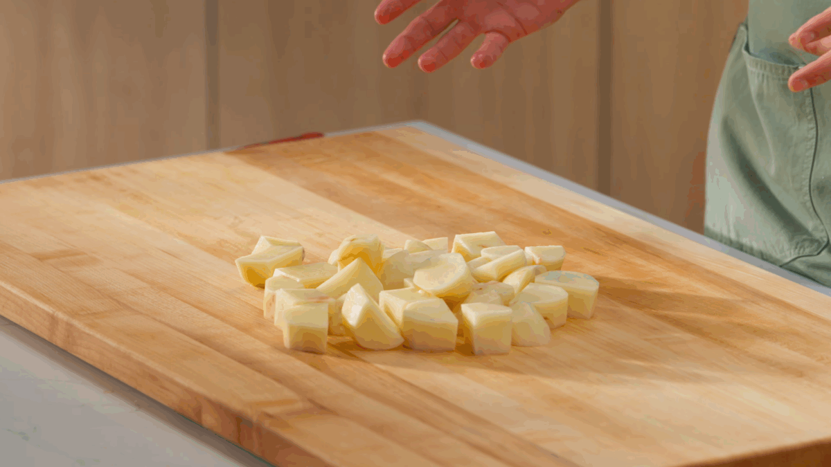 Peeled and cubed potatoes on a wooden cutting board. 