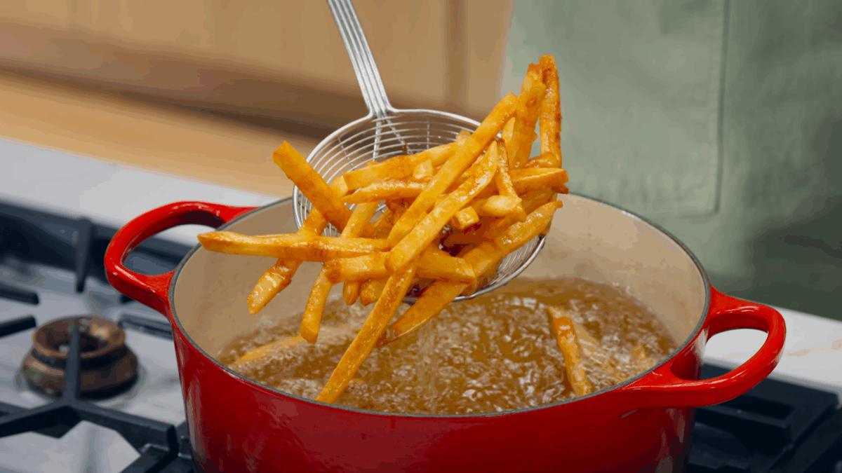 Nick DiGiovanni lifting homemade French fries from a pot.