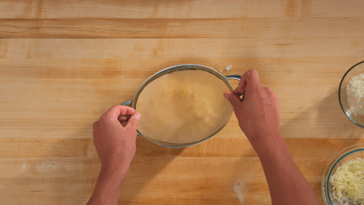 Nick DiGiovanni placing a disc of parchment paper over potato gratin. 