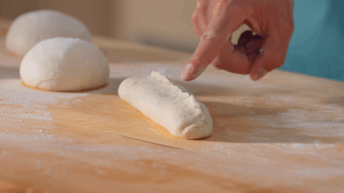 Nick DiGiovanni shaping bahn mi bread dough into baguettes.