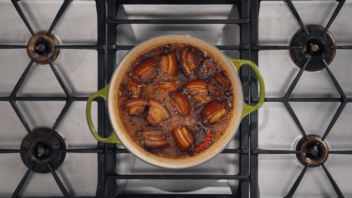 Pork belly pieces braising in a caramel sauce.
