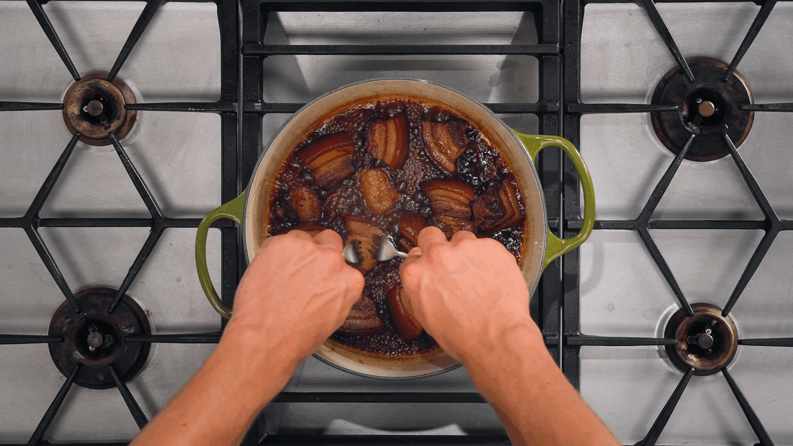 Nick DiGiovanni shredding caramelized pork in a Dutch oven.