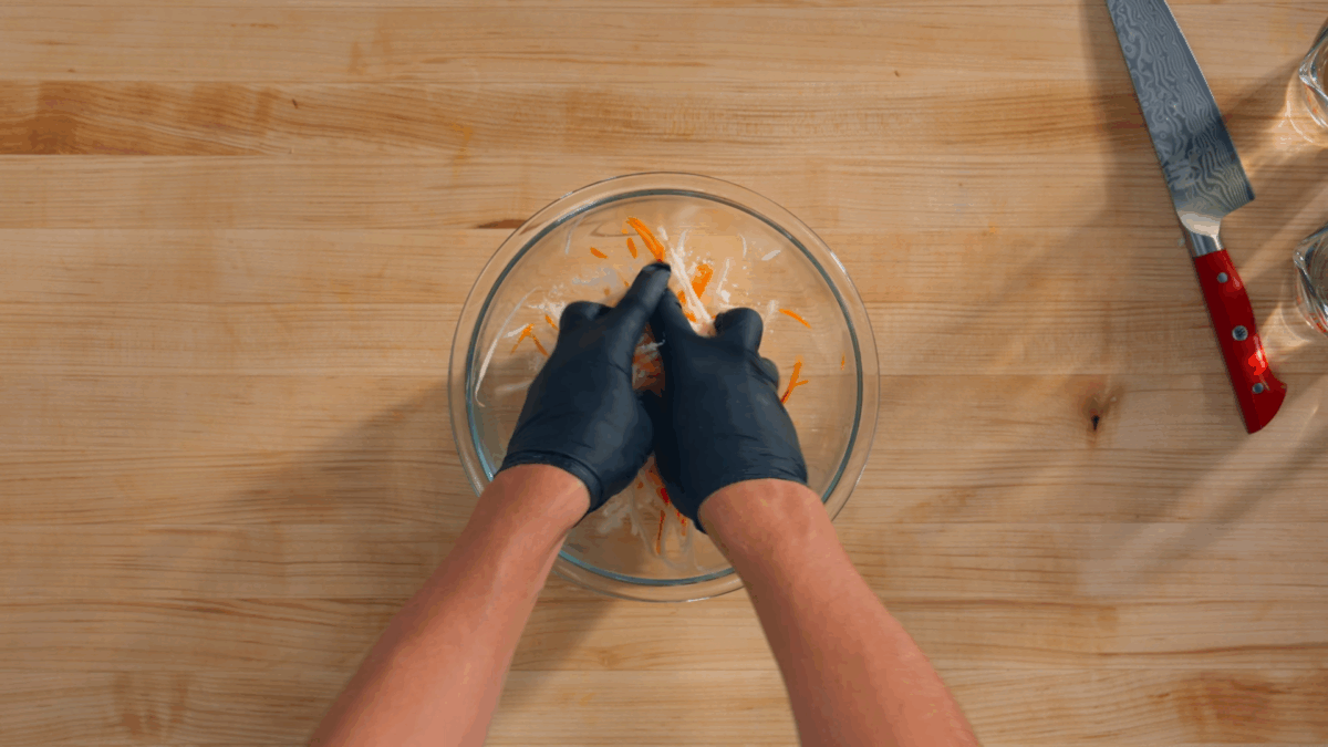 Nick DiGiovanni rubbing sugar ans salt into julienned carrots and radish.