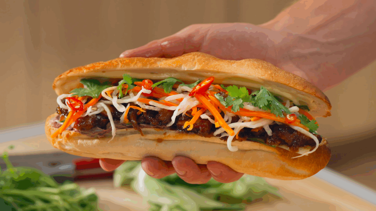 Nick DiGiovanni holding a caramelized pork banh mi sandwich. 
