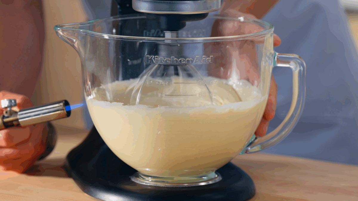 Nick DiGiovanni using a torch to heat an egg and sugar mixture being whipped in a stand mixer. 
