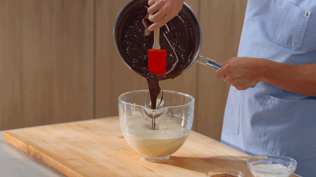 Nick DiGiovanni scraping a melted chocolate mixture into a bowl of whipped eggs and sugar. 