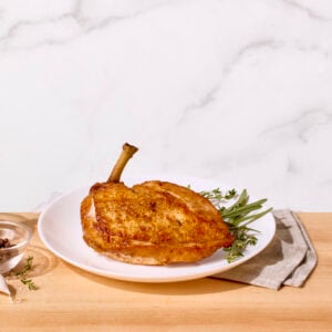 A brined and pan-roasted chicken. breast on a plate.